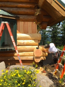 One of the Tip Top Construction contractors performing precision work on a log home siding project.